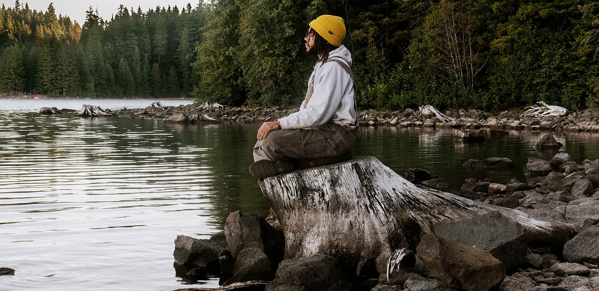 A person meditating on the side of a lake