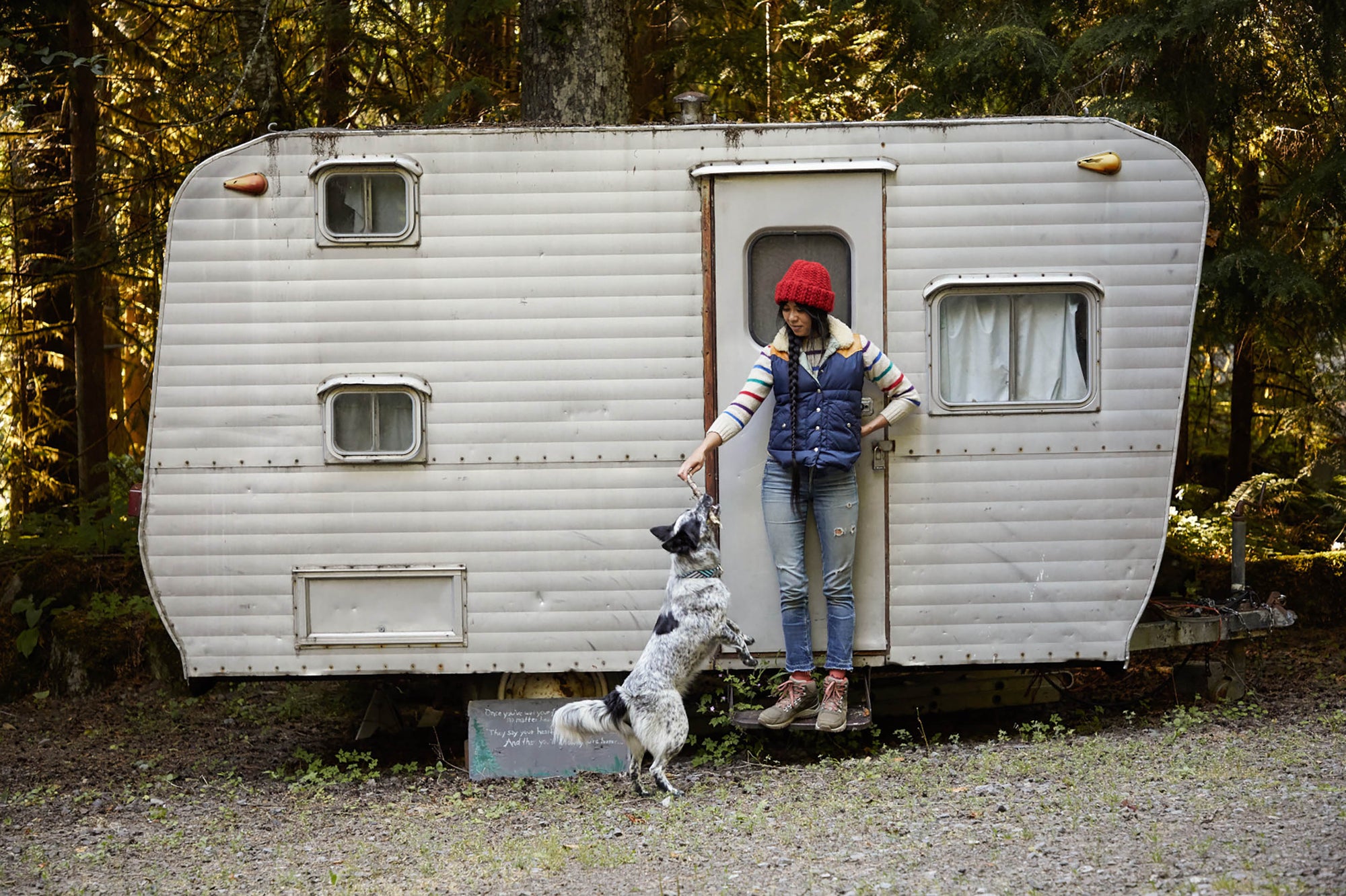 woman standing on doorstep of a small RV playing with a dog