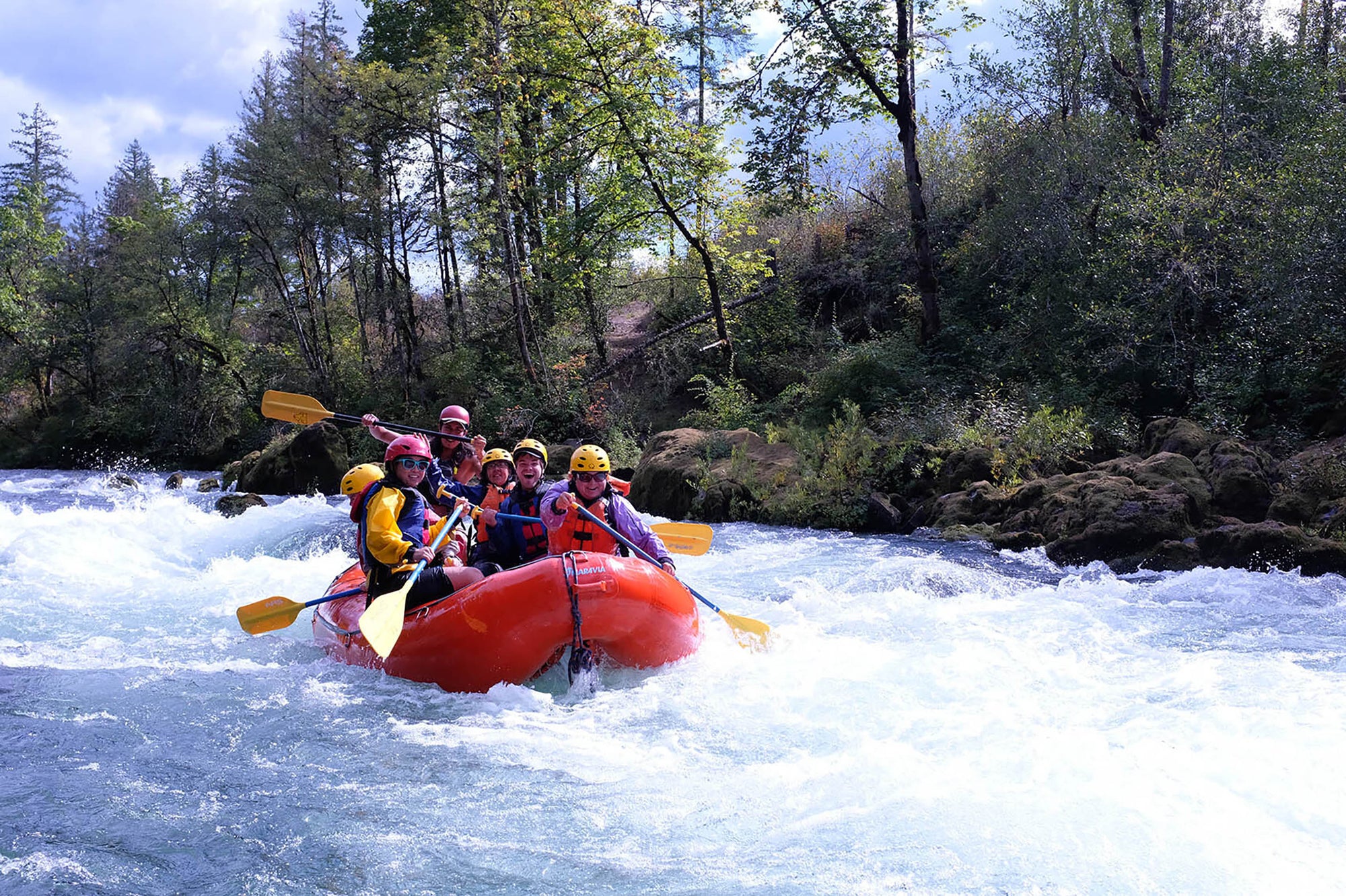 group of people in a raft going through white water rapids