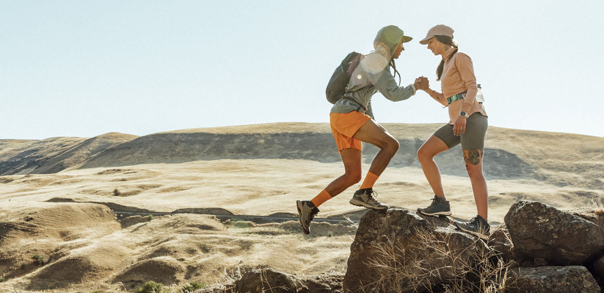 two people grasp hands while on a hike